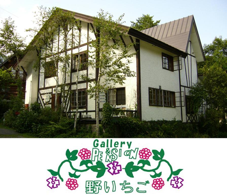 Uma casa branca com um cartaz à frente. em Gallery & Lodge Noichigo em Hakuba