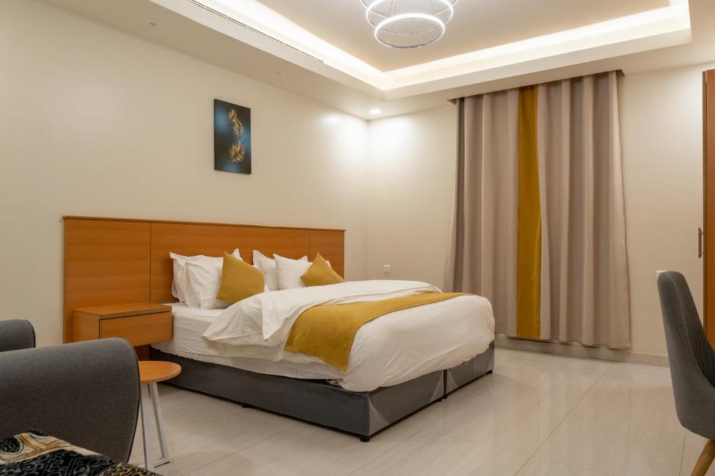 ein Schlafzimmer mit einem großen Bett mit weißen und gelben Kissen in der Unterkunft Al Nakheel Park Serviced Apartment in Riad