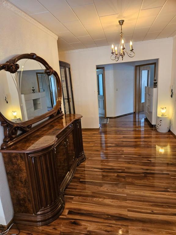 een kamer met een spiegel op een houten vloer bij Großes Haus mit Kamin und Garten in Baunatal