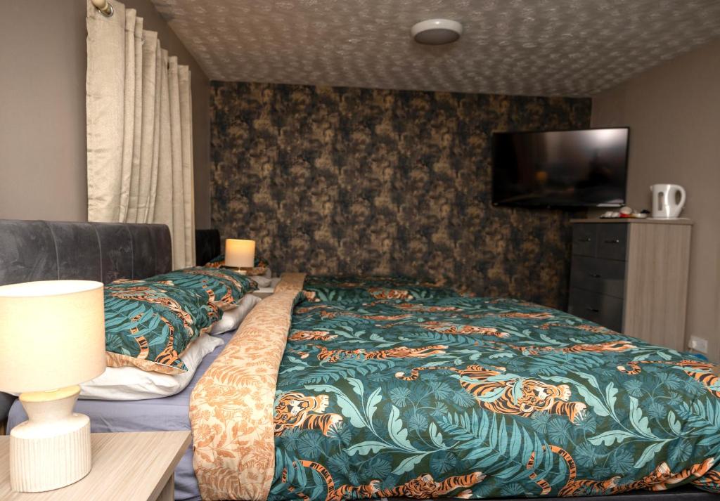 um quarto com uma cama com um cobertor e uma televisão em Castle Inn em Newtownstewart