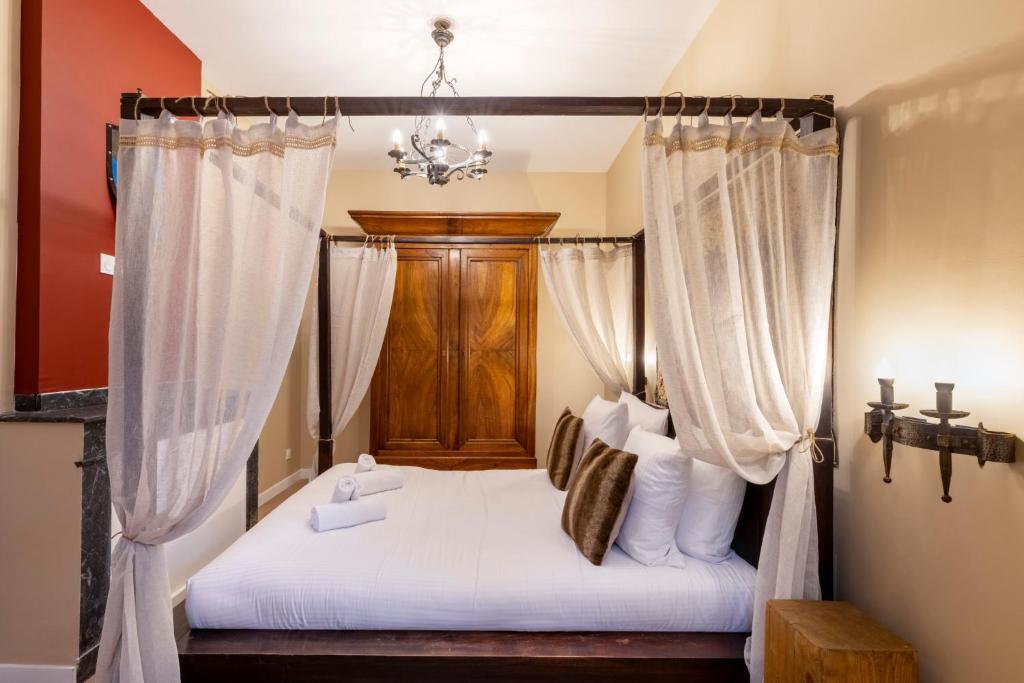 ein Schlafzimmer mit einem Himmelbett mit weißer Bettwäsche und Kissen in der Unterkunft Balda'Quand Médiéval in Carcassonne