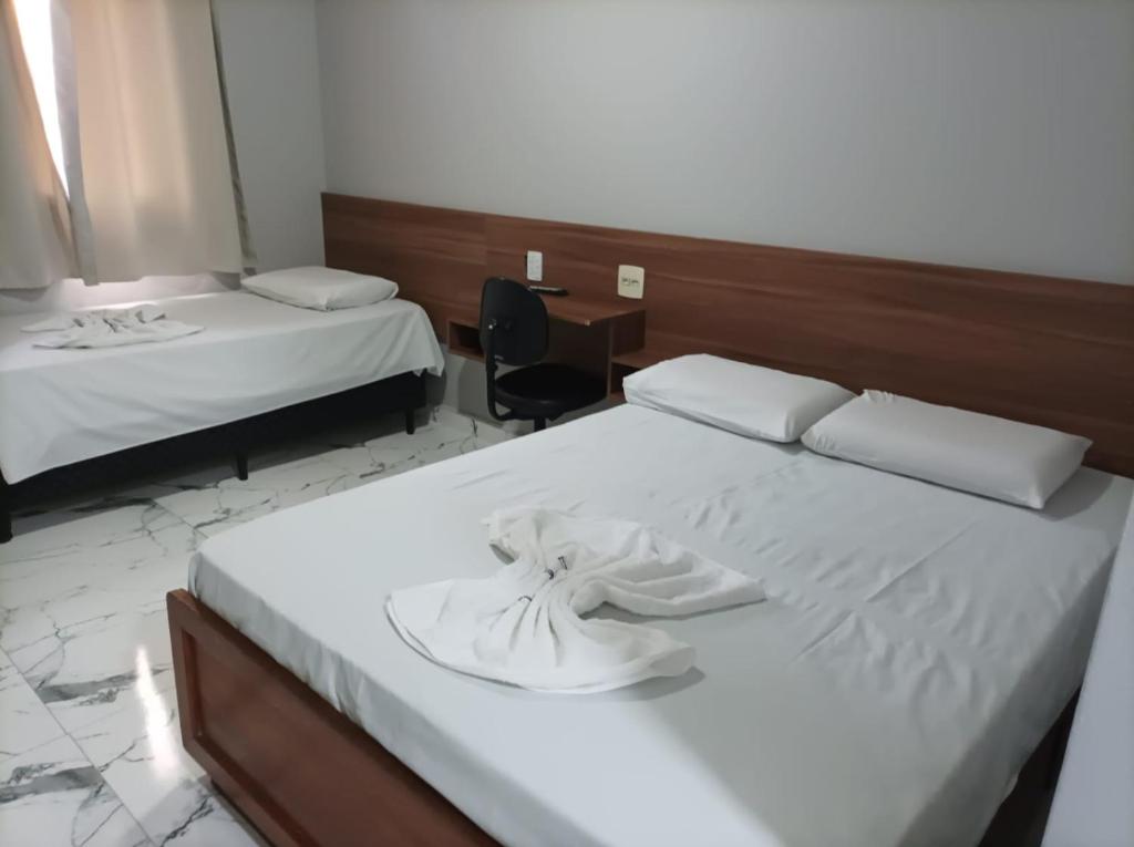 a hotel room with two beds and a desk at Hotel Rio Claro in Rio Claro