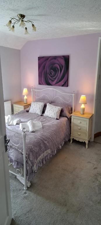ein Schlafzimmer mit einem Bett und zwei Nachttischen mit Lampen in der Unterkunft Wisteria Cottage an authentic and enchanting 2 bedroom cottage experience in Aberdare