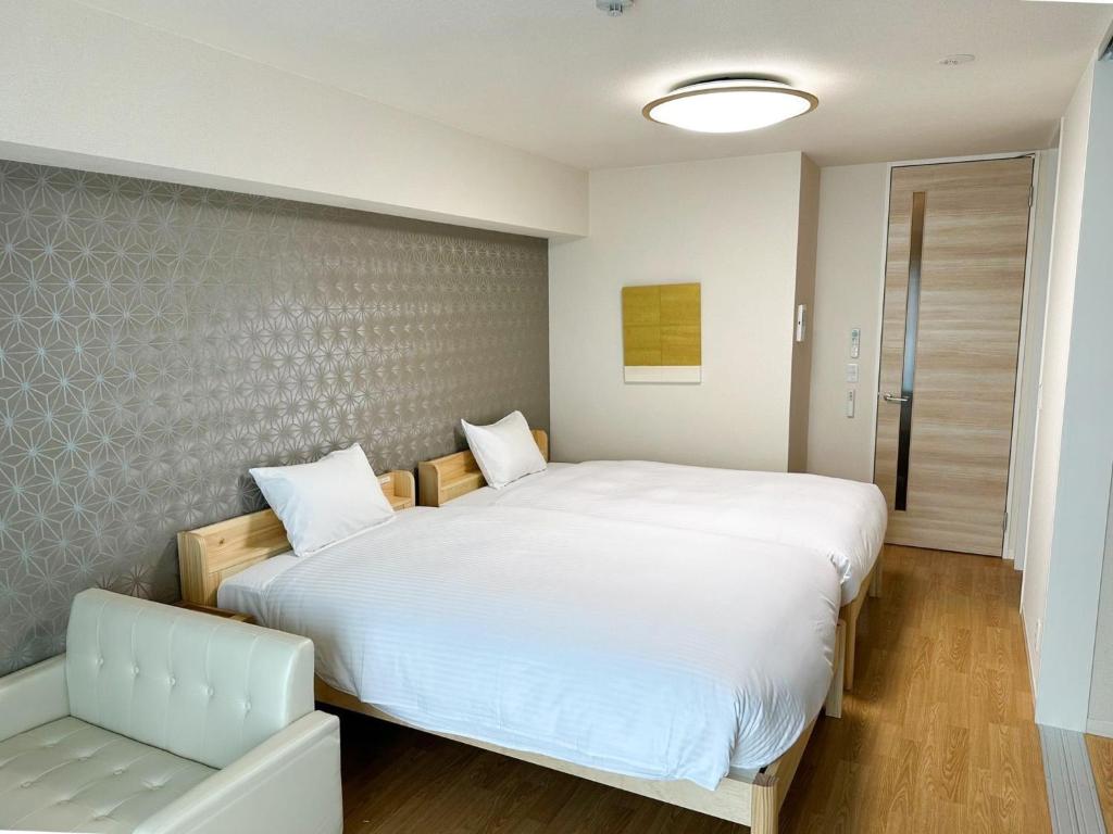 een slaapkamer met een groot wit bed en een stoel bij RakutenSTAY x Shamaison Osaka Dekijima - Vacation STAY 12317 in Osaka