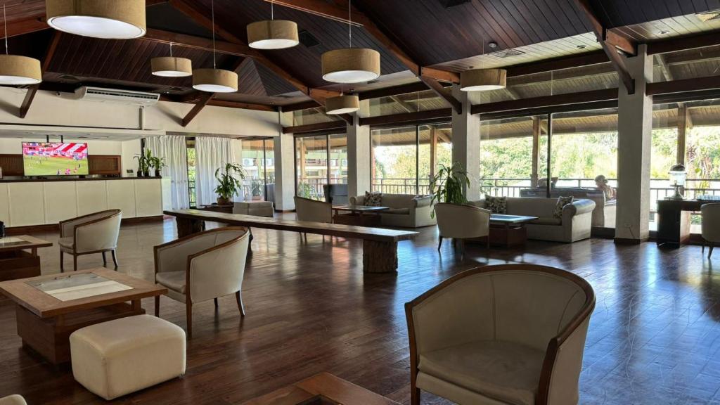 a large lobby with chairs and tables and windows at Hotel Raices Esturion in Puerto Iguazú