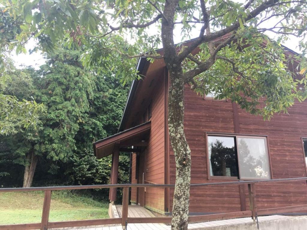 una casa de madera con un árbol delante en Eco Park Ronshohara - Vacation STAY 41985v, en Unzen