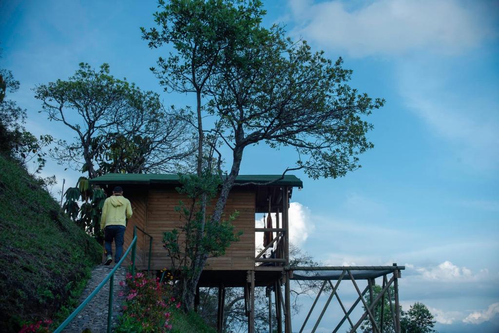 Un uomo in piedi sulle scale di una casa sull'albero di Eco Hotel The View a El Peñol