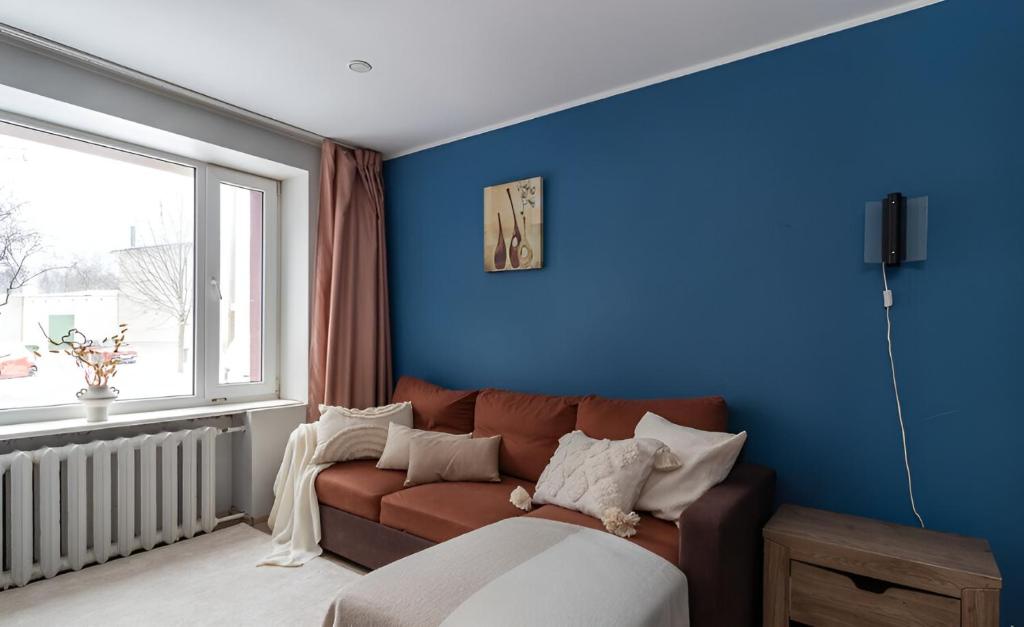 Cozy apartment near the sea في تالين: غرفة معيشة مع أريكة بنية أمام الجدار الأزرق