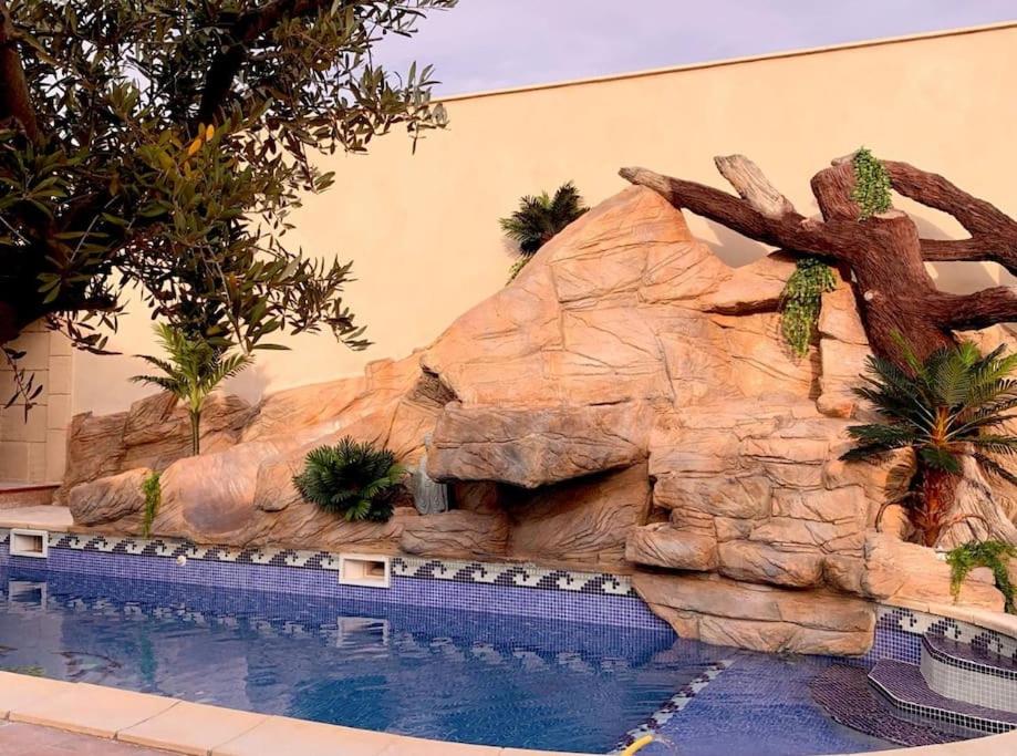 een zwembad voor een rotswand bij Villa 4P piscine avec toboggan et cascade in Bessan