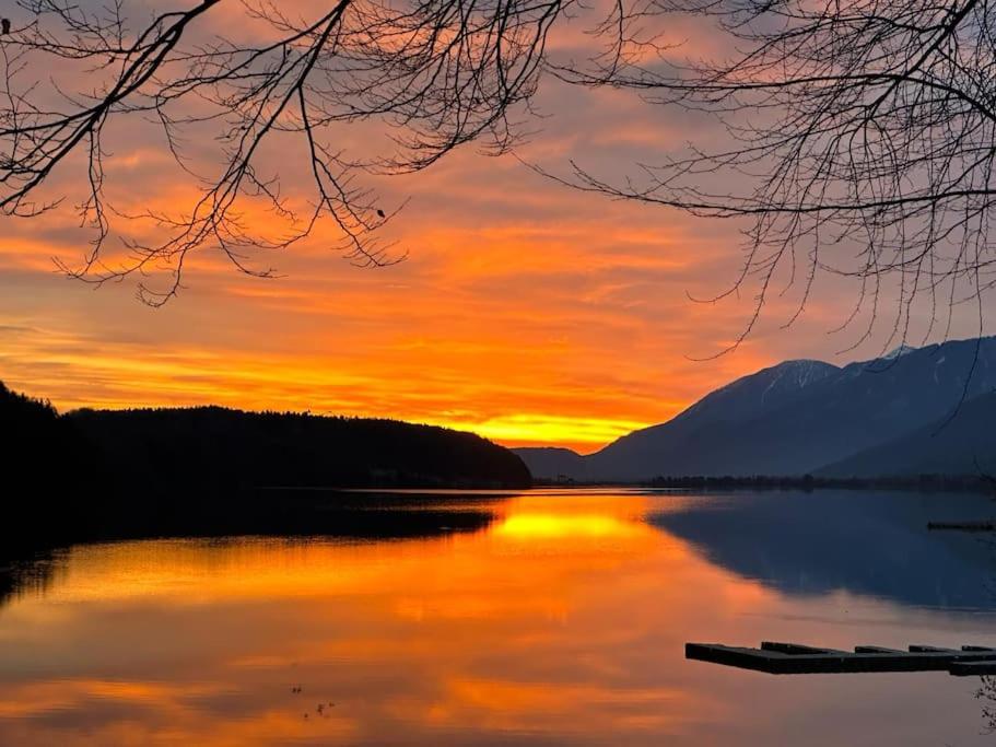 un coucher de soleil sur une étendue d'eau avec un quai dans l'établissement Haus an der Drau, à Feistritz im Rosental