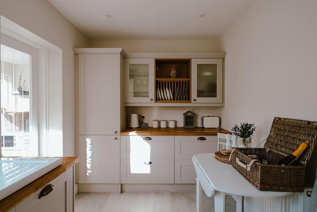cocina con armarios blancos y mesa en Modern Cottage Style House with Log Burner en Harrogate