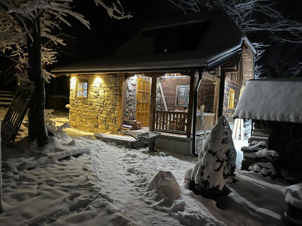uma casa coberta de neve à noite em Brvnara Iverak em Mokra Gora