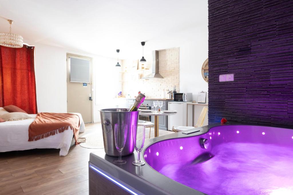 ein Bad mit einer lila Badewanne in einem Zimmer in der Unterkunft Loft Romantique - Spa Privatif - Spa Noctambulles in Hyères
