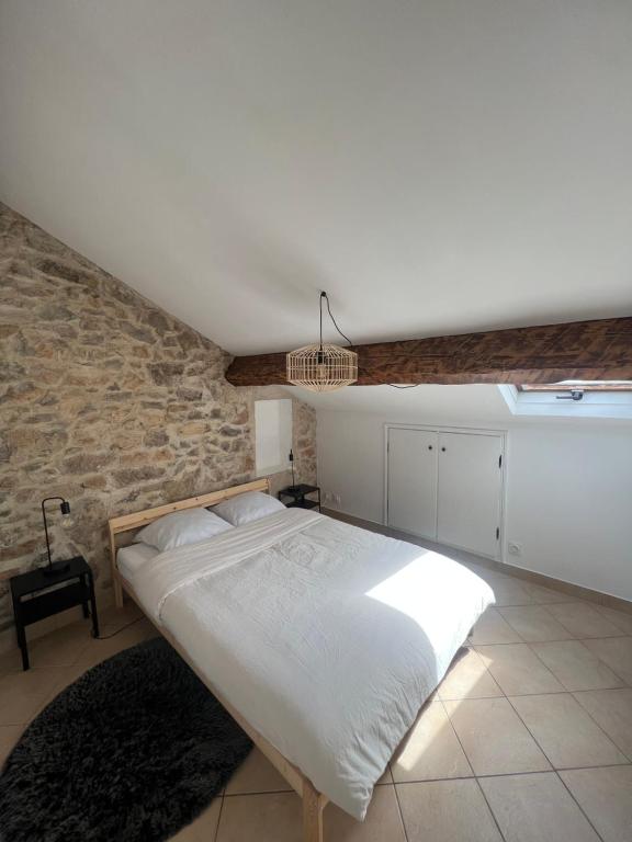 une chambre avec un grand lit dans un mur de pierre dans l'établissement Sous les toits de Golfe Juan, 2 à 4 personnes, à Vallauris