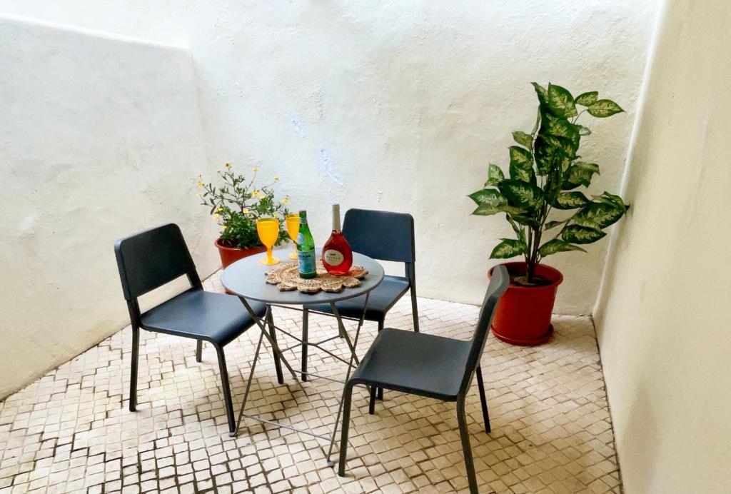 une table et des chaises avec des boissons et une plante en pot dans l'établissement Lisbon Charming Santos Apartment w/ Patio, à Lisbonne
