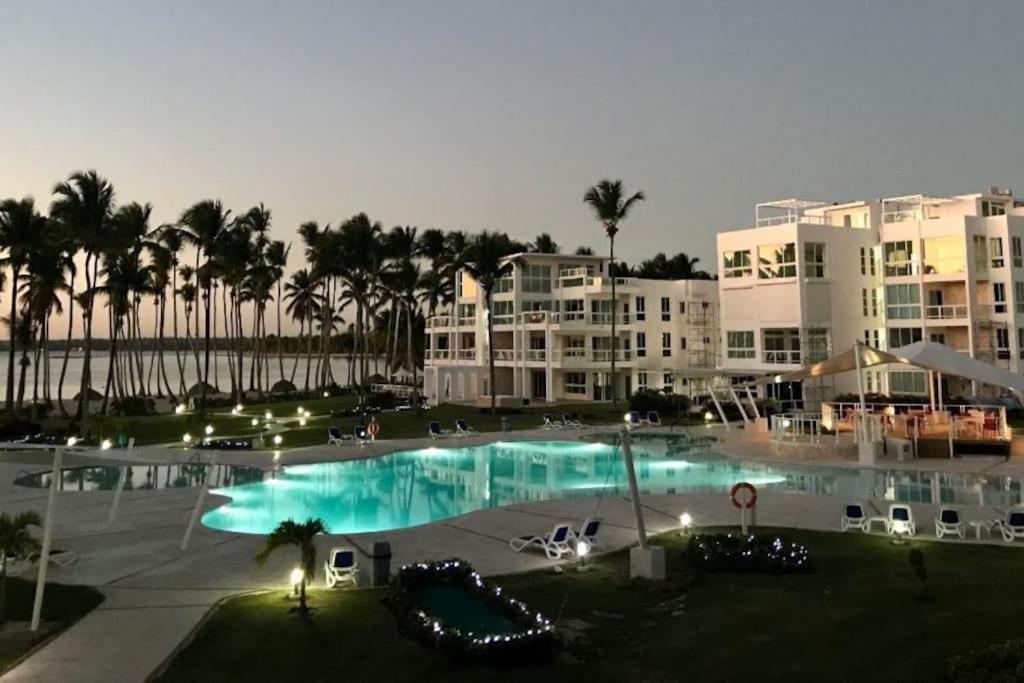 a large swimming pool with palm trees and buildings at Gourgeous 2 bedroom Beach Apt Playa Nueva Romana in San Pedro de Macorís