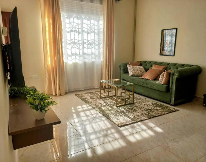 a living room with a green couch and a table at Lovely Double Bed with a Private Garden Nook in Kira