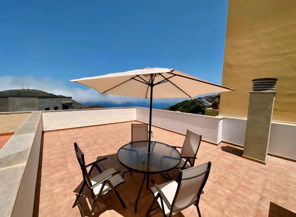 a table and chairs with an umbrella on a roof at Vivienda Vacacional VillaVerde in Valverde