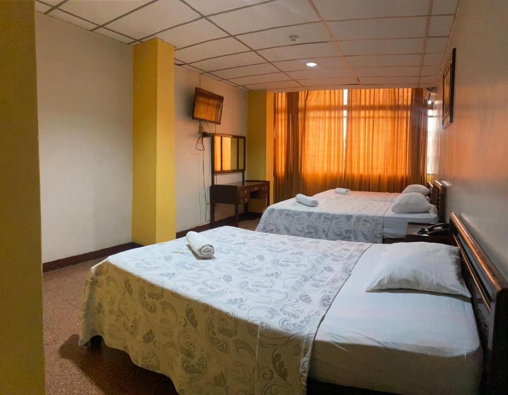 a hotel room with two beds and a window at Hotel Andes INN in Guayaquil