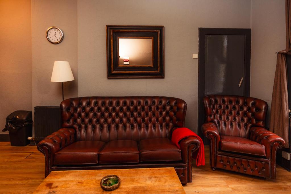 a brown leather couch and two chairs in a room at Warm, Cozy&Relaxed Apartment by Holyrood Palace in Edinburgh