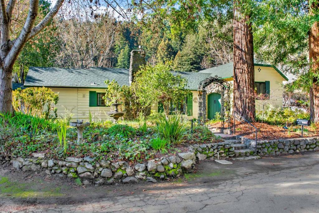 una casa amarilla con un árbol y una pared de piedra en Rivendell, en Monte Rio