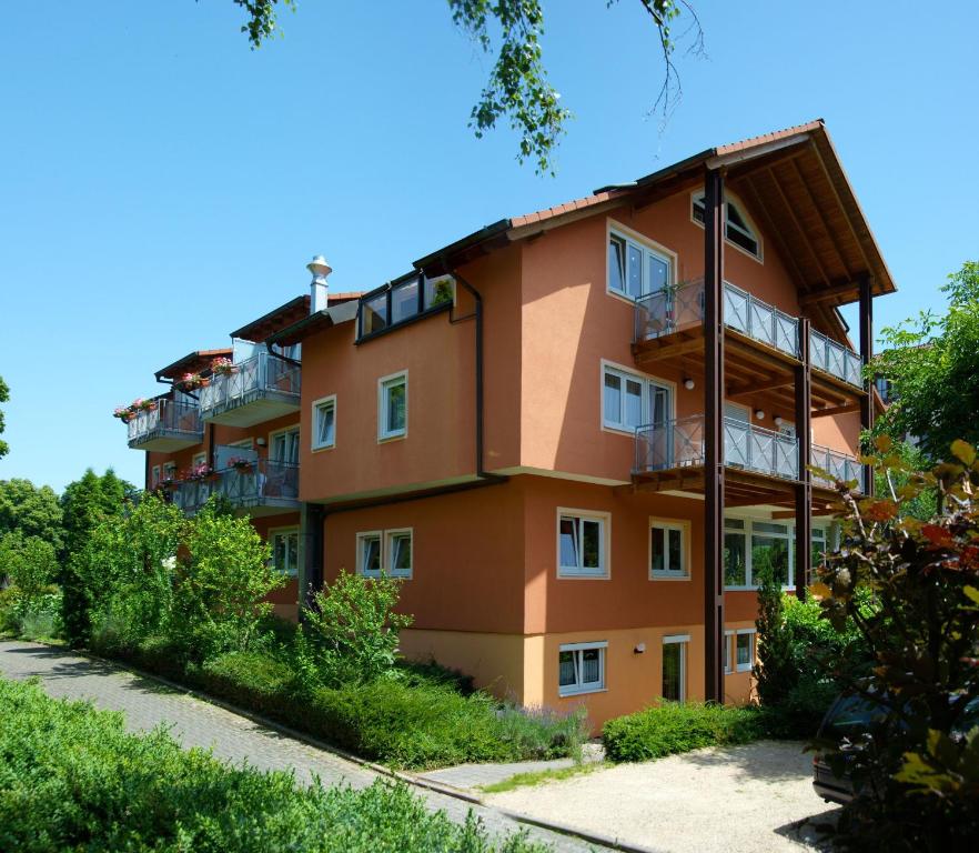 ein orangefarbenes Apartmenthaus mit Balkonen und Bäumen in der Unterkunft Thermen Appartements Gabriela in Bad Krozingen