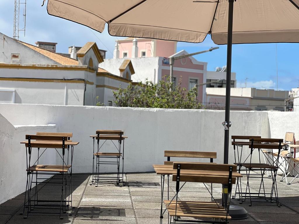 een groep tafels en stoelen met een paraplu bij Casa Sebastião in Faro