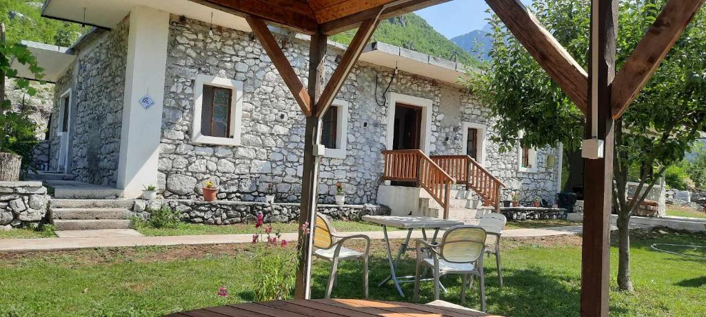ein Steinhaus mit einem Tisch und Stühlen im Hof in der Unterkunft Stomici Guesthouse in Ndërlysaj