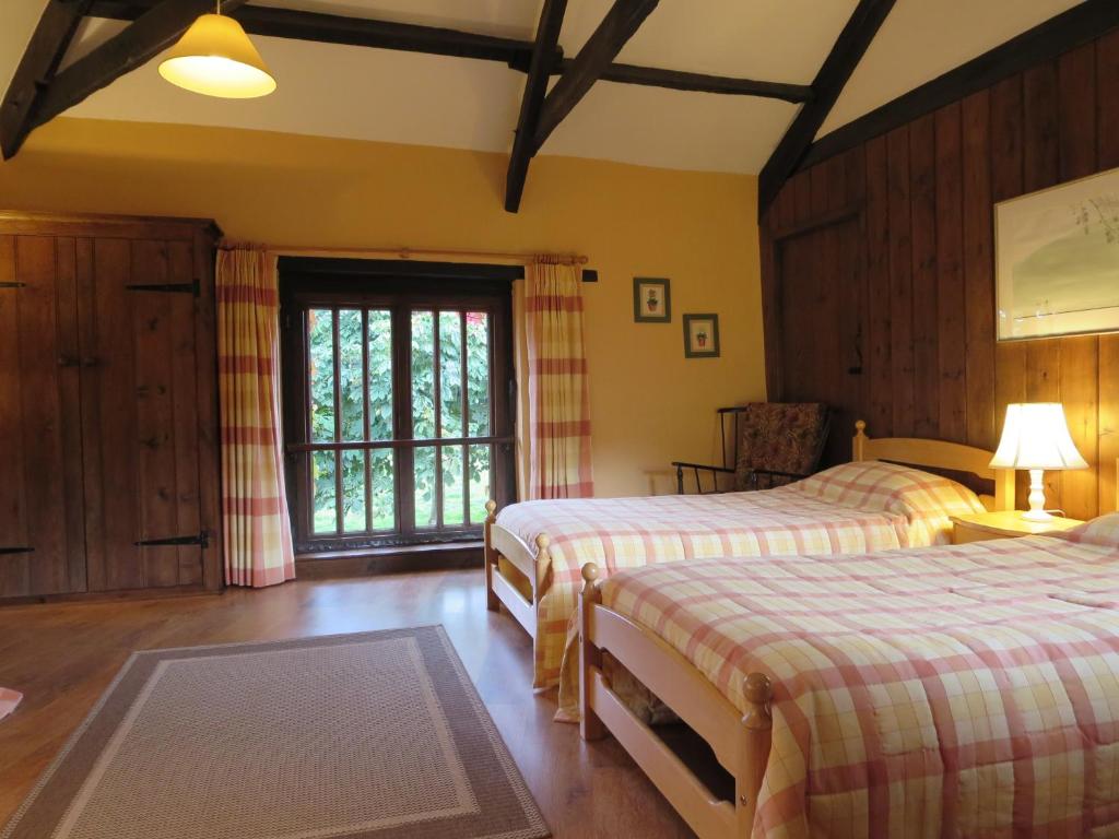 1 dormitorio con 2 camas y ventana en Combe Lancey Farmhouse B&B en Crediton