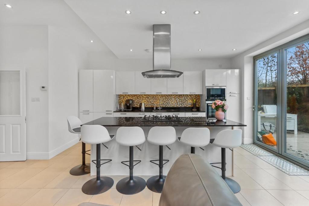 a kitchen with a island with stools and a counter top at Windsor House near the Park in Hendon
