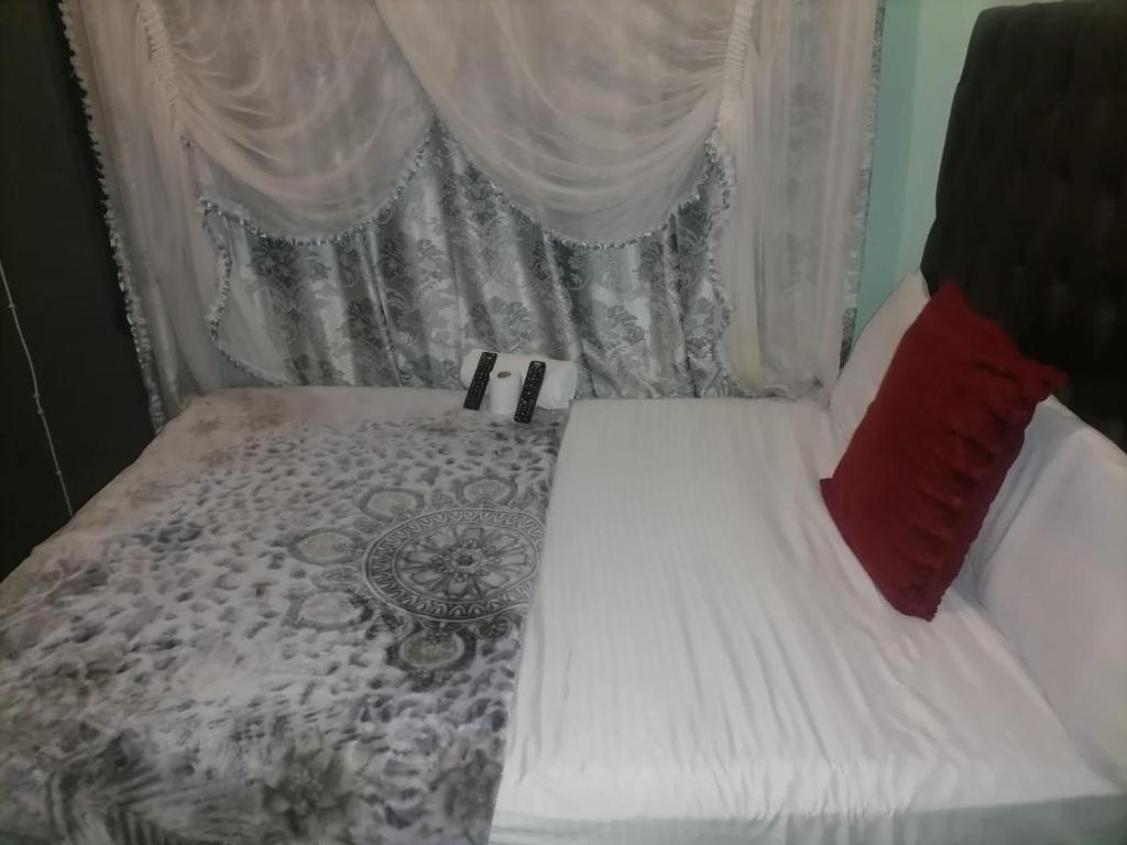 a bed with a white comforter and red pillows at Guest room florida in Roodepoort