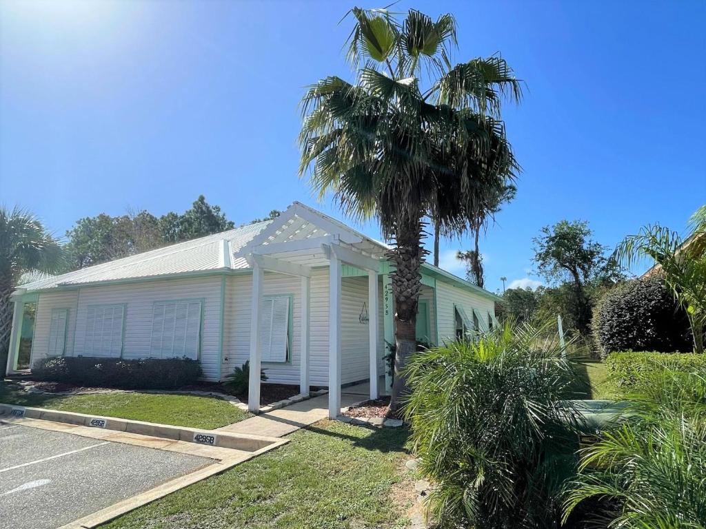 a white house with a palm tree in front of it at Seaglass @ Orange Beach Villa in Orange Beach