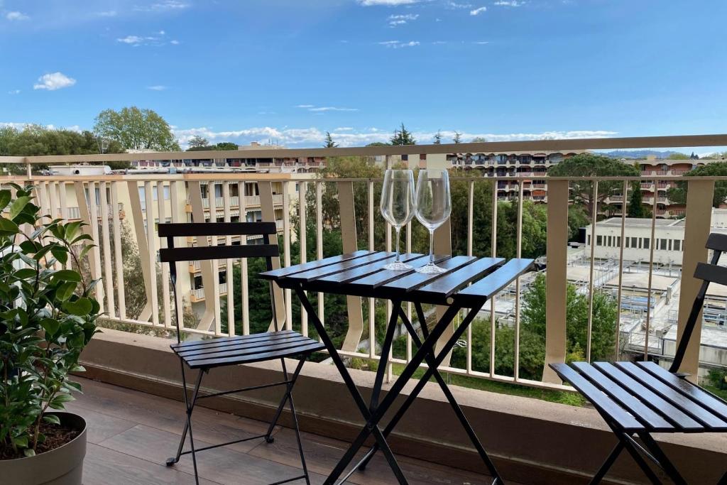 una mesa con 2 copas de vino y 2 sillas en el balcón en Cosy T2 at 10 minutes from the sea!, en Mandelieu-la-Napoule