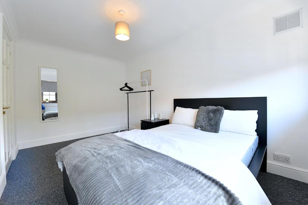 a bedroom with a white bed with a black headboard at Large home near central London in London