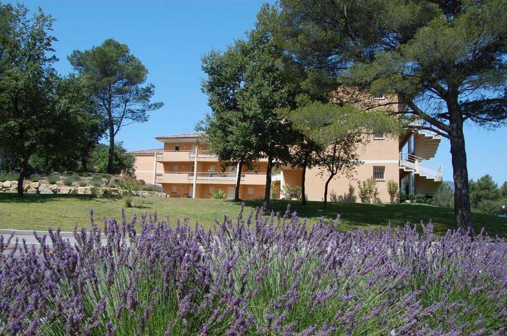 a building with trees and purple flowers in the foreground at Résidence Côté Sud Peypin in Peypin