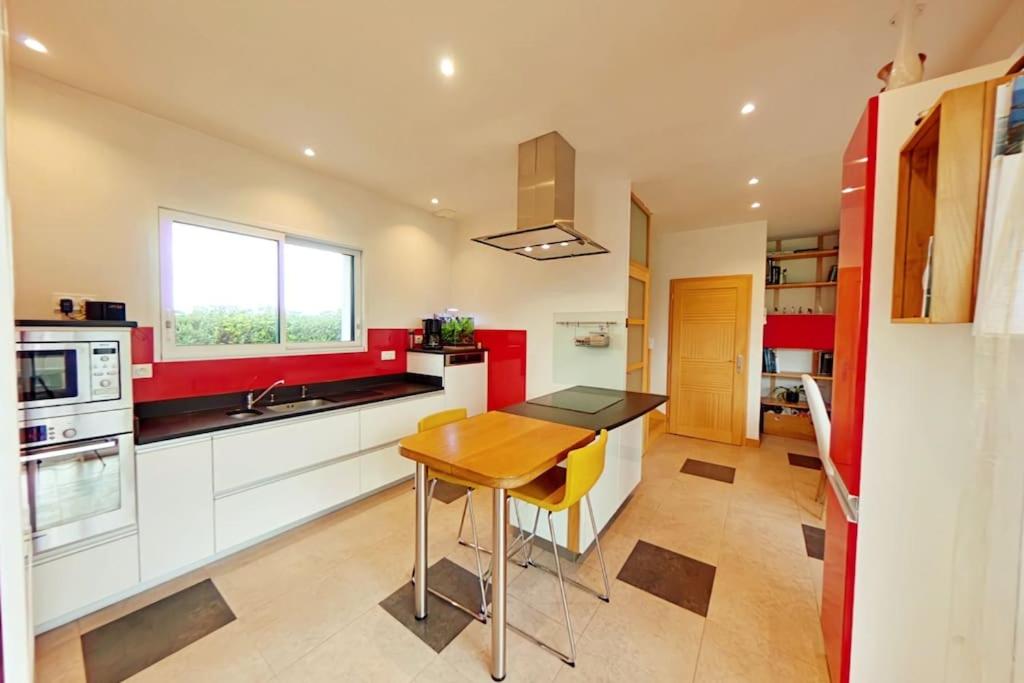 a kitchen with red and white cabinets and a wooden table at Maison de vacances, chaleureuse, avec sauna in Santec