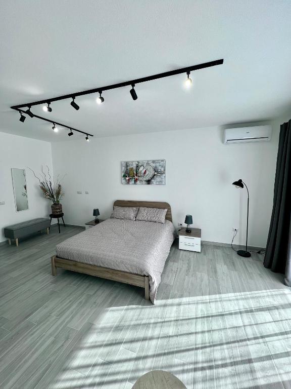 Dormitorio blanco con cama y luces en el techo en Sunset Street - La residenza del centro en Arborea 