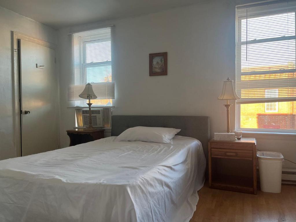 um quarto com uma cama branca e 2 janelas em 2131 em Filadélfia