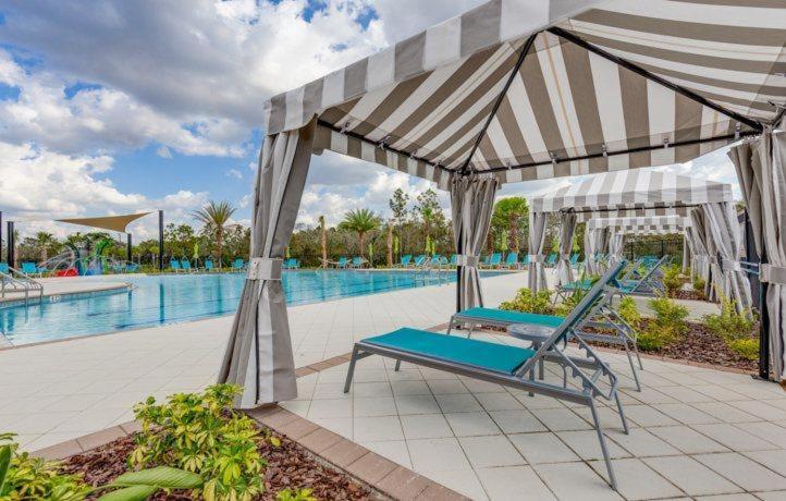 a pool with two lounge chairs under a canopy at Maggie's Cozy Corner in Wimauma