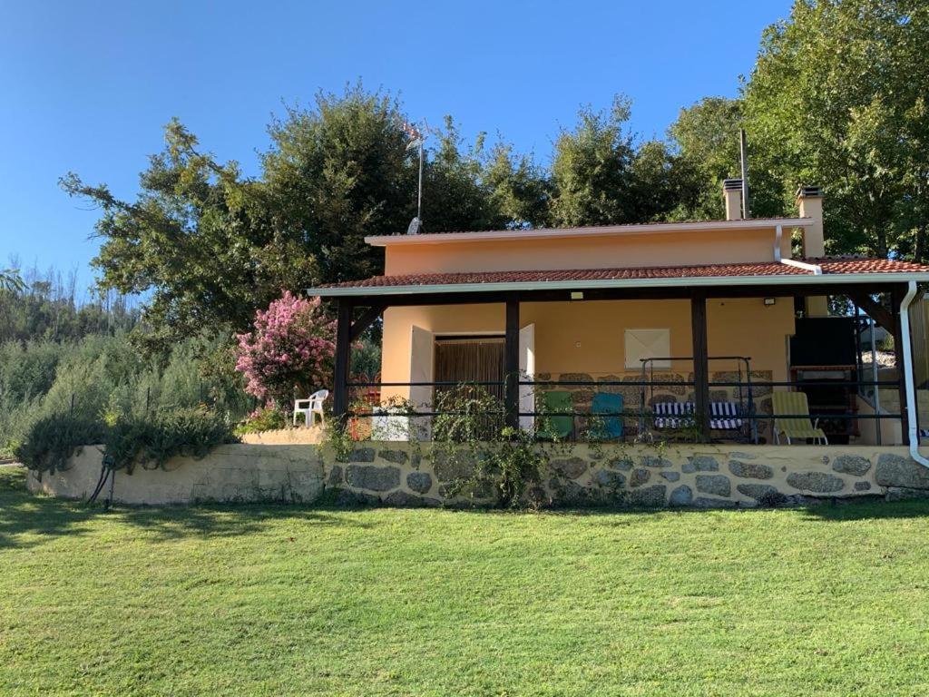 una pequeña casa con un campo verde y árboles en Quintinha do Rio, en Treixedo