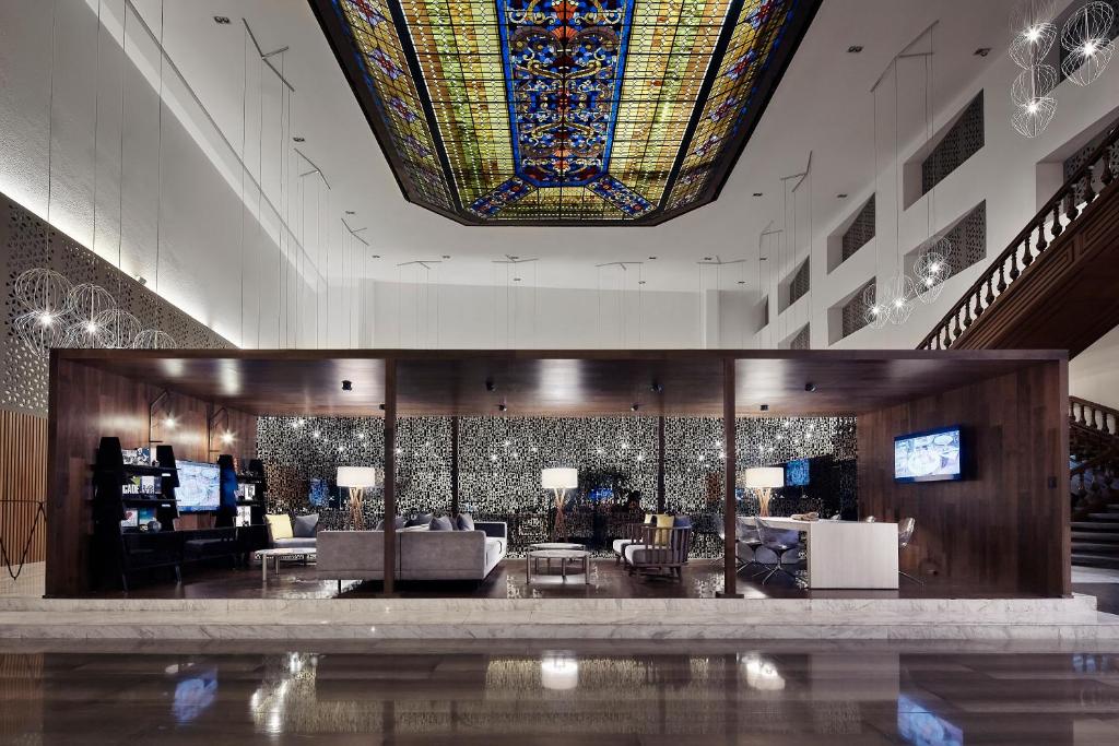 un vestíbulo con un gran techo de vidrieras y una sala de estar. en Wyndham Monterrey Ambassador Centro en Monterrey