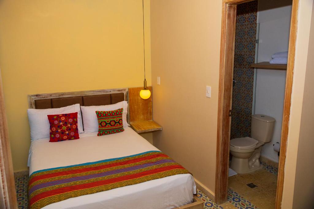 a small bedroom with a bed with colorful pillows at Coco Beach Hotel - Rooftop & Beach Club in Cartagena de Indias