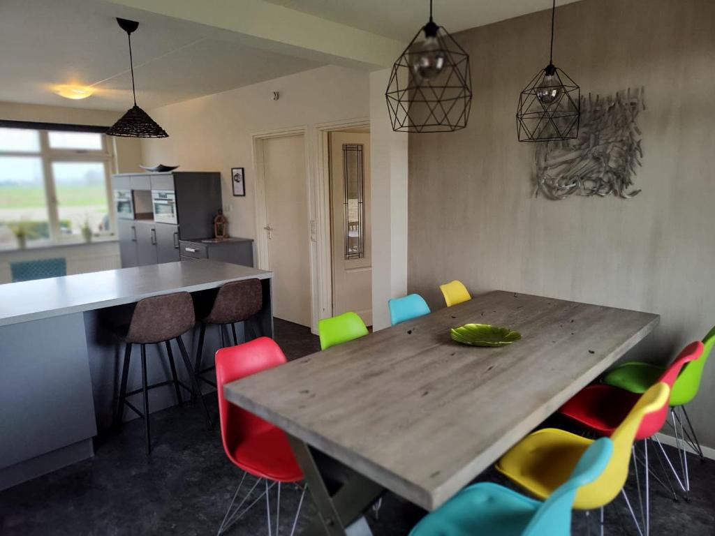 uma cozinha com uma mesa de madeira e cadeiras coloridas em 8 person farmhouse with sauna em Toldijk