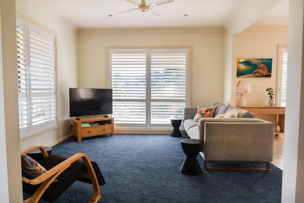a living room with a couch and a flat screen tv at Charming Cottage, 7 mins walk to the beach and golf! in Torquay