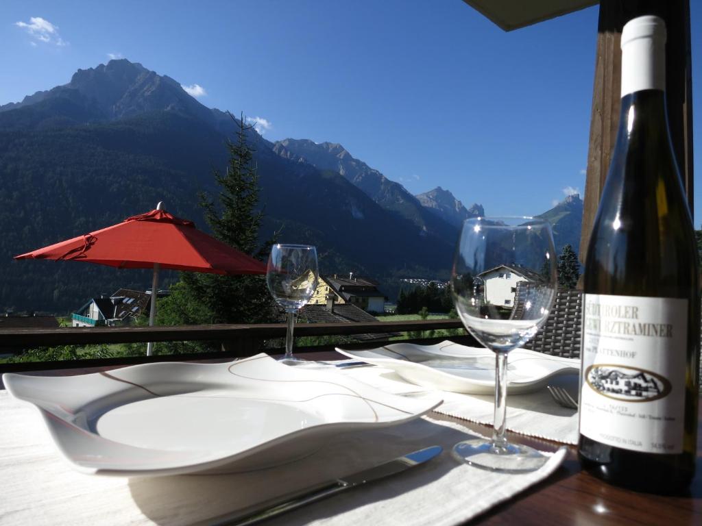 una mesa con una botella de vino y dos copas en Ferienwohnung Eller, en Telfes im Stubai