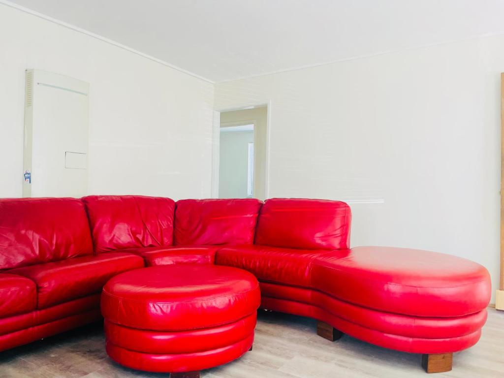 a red couch with two red ottomans and a stool at House in Thomastown in Melbourne