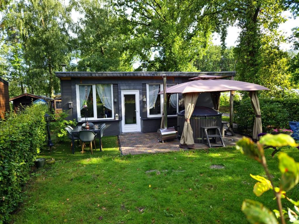 a blue tiny house with an umbrella in a yard at Chalet met hottub in Lanaken
