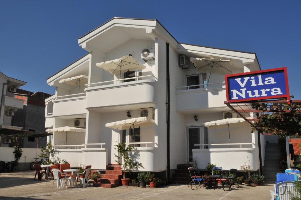 a white building with tables and chairs in front of it at Guest House Nura in Ulcinj