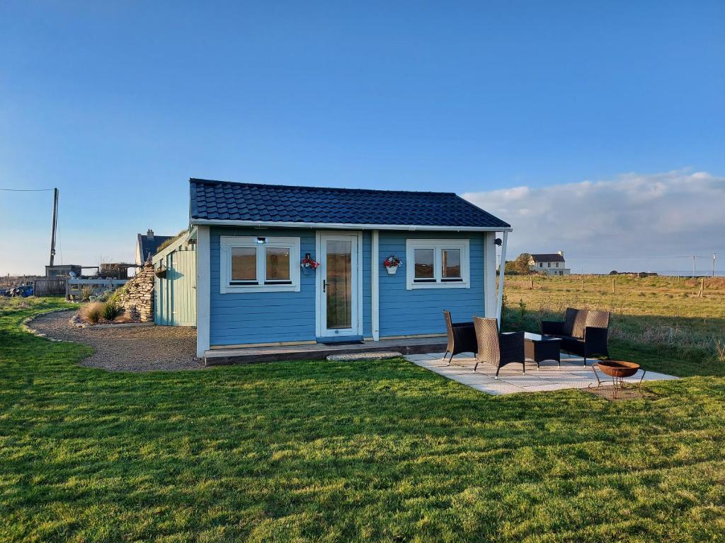 a blue tiny house in the middle of a field at Seafield Cabin in Tromra