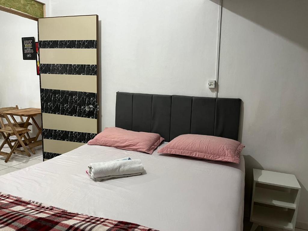 a bed with two pink pillows on top of it at Apartamento no Centro de Blumenau in Blumenau